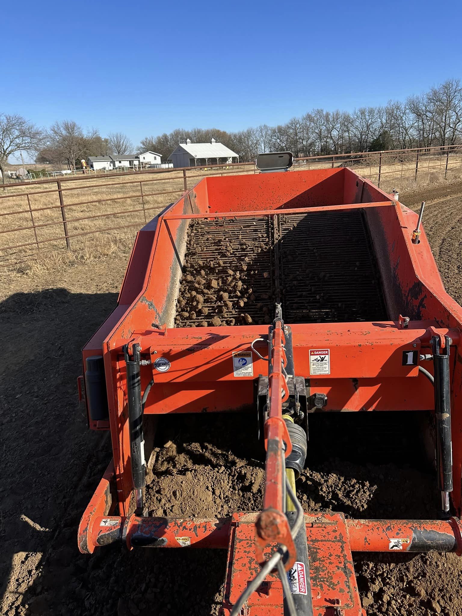 Portion of a red machine that serves holds a load of material collected from the ground.